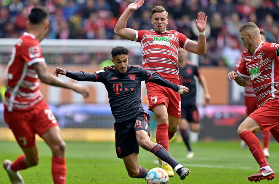 Pemain Augsburg berbaju merah sedang mengepung pemain Bayern