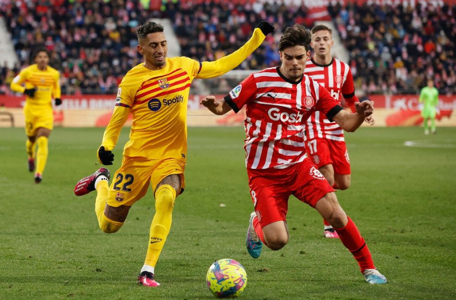 Pemain Girona berseragam kotak-kotak merah putih dalam pertandingan memperebutkan bola 