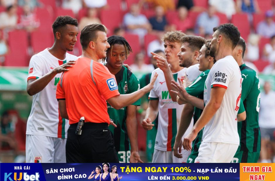 Kubet cập nhật hình ảnh các cầu thủ Augsburg trong trang phục màu trắng đang cự cãi với trọng tài trong một pha phạm lỗi 