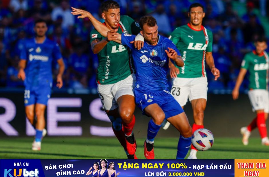 Kubet cập nhật hình ảnh cầu thủ Getafe trong trang phục thi đấu màu xanh thiên thanh đang tranh bóng với cầu thủ Alaves.