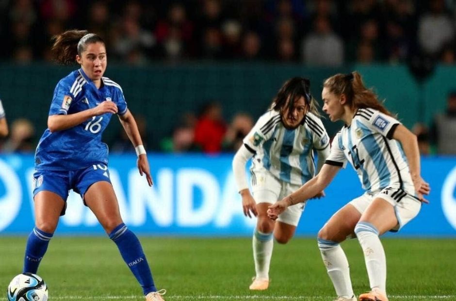 Cầu thủ nữ tuyển Italia trong trang phục áo màu thiên thanh đang đối đầu với các cô gái phòng ngự bên phía Argentina.