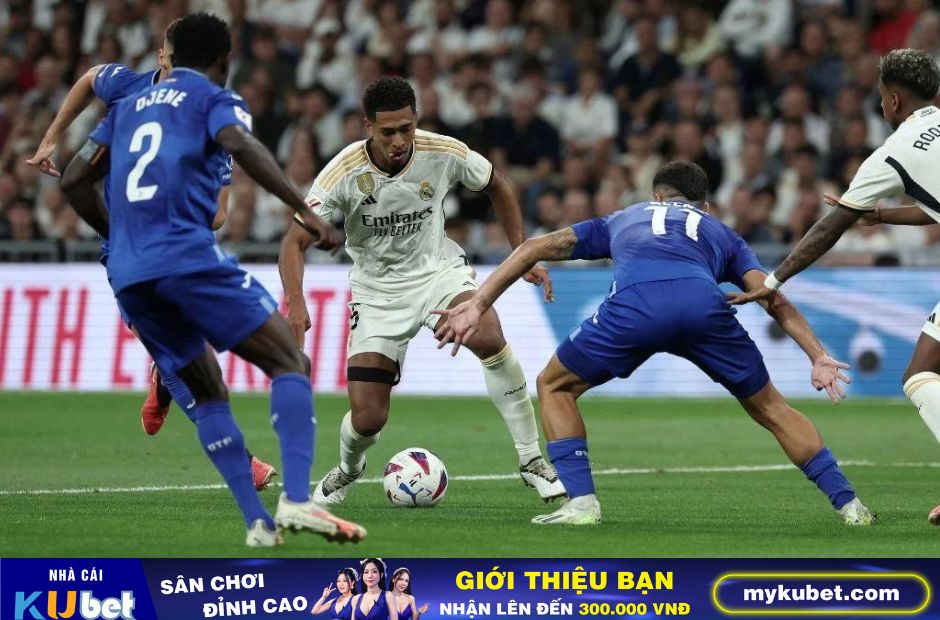 Kubet cập nhật hình ảnh các cầu thủ Getafe trong trang phục màu xanh đang vây công Bellingham của Real Madrid